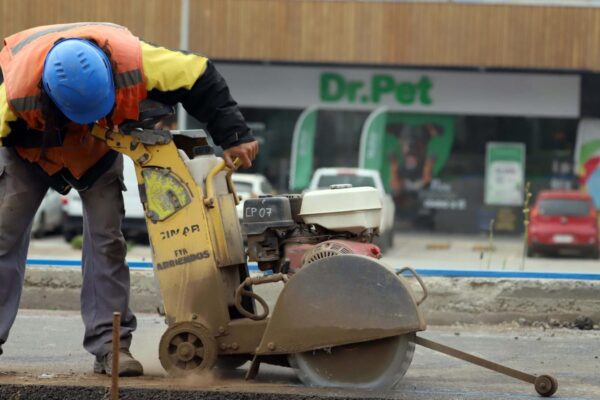 Trabajador con casco opera una cortadora de pavimento en una calle