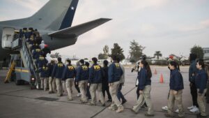 Detectives de la PDI escoltan a extranjeros expulsados que suben a un avión de la FACh