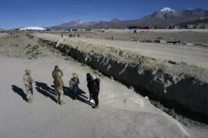 Militares y civiles junto a una zanja excavada en la frontera norte, con volcanes al fondo