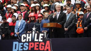 Presidente Kast habla en un podio junto a trabajadores con cascos durante el lanzamiento de Chile Despega