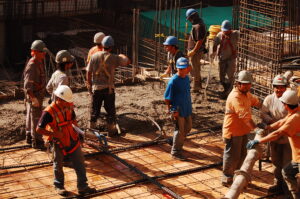 Trabajadores de la construcción con cascos y chalecos reflectantes en una obra