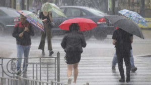 Personas con paraguas cruzan una calle bajo la lluvia