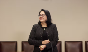 Funcionaria de la Contraloría de pie en una sala de reuniones