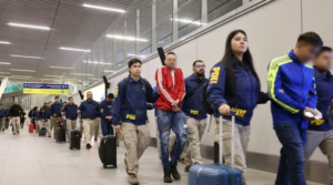 Extranjeros expulsados caminan con maletas escoltados por detectives de la PDI en el aeropuerto