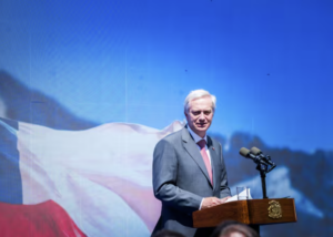 Presidente Kast habla en un podio frente a una gran bandera chilena proyectada
