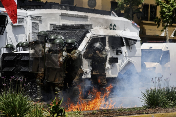 Carabineros de fuerzas especiales junto a un carro policial alcanzado por una molotov en la Alameda