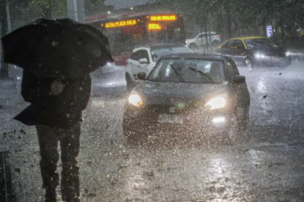 Peatón con paraguas bajo una lluvia intensa junto al tráfico en Santiago
