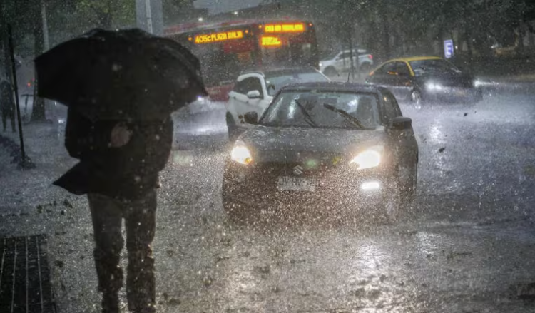 Peatón con paraguas bajo una lluvia intensa junto al tráfico en Santiago
