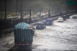 Autos y un camión avanzan por una autopista inundada durante el sistema frontal en Santiago