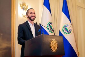 Presidente de El Salvador habla en un podio junto a banderas salvadoreñas