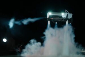 Tesla Roadster suspendido en el aire sobre una nube de humo de sus propulsores